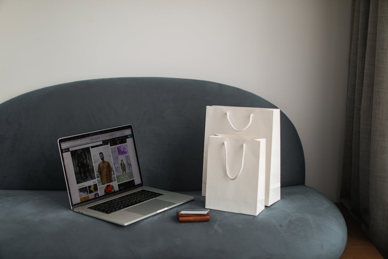 Online shopping setup with a laptop and shopping bags on a stylish couch.